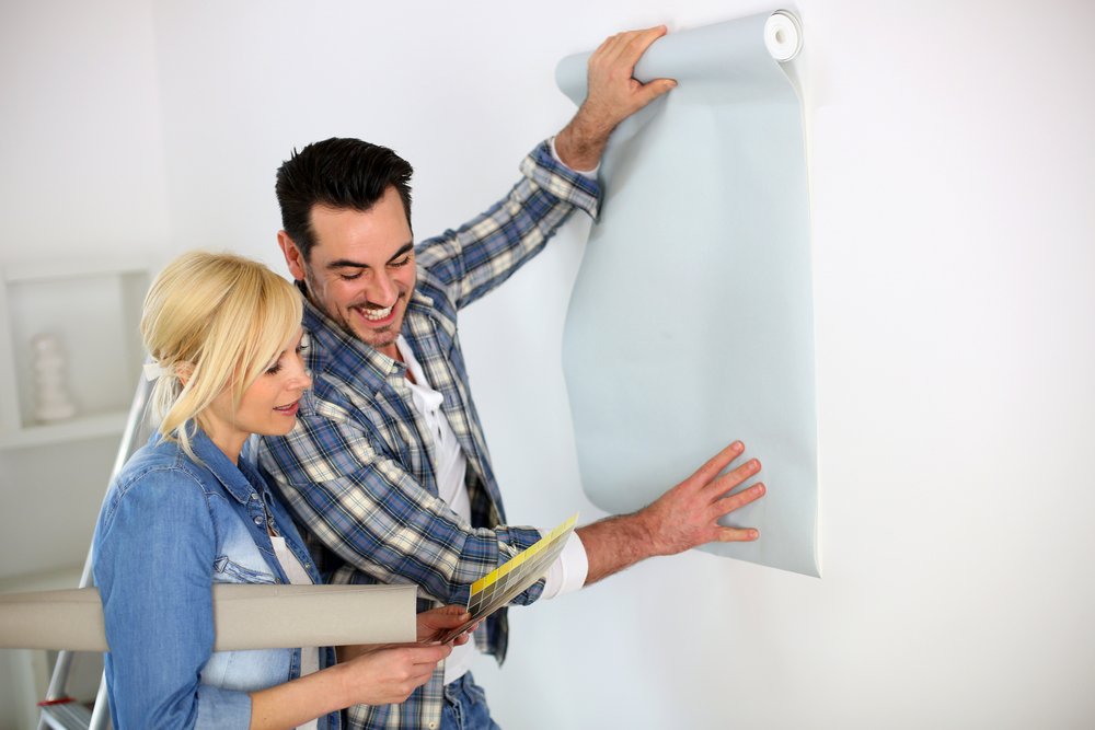 Een persoon brengt glasvezelbehang aan op een muur, illustrerend het proces van behangen met glasvezelbehang voor een duurzame en veerkrachtige muurbekleding.